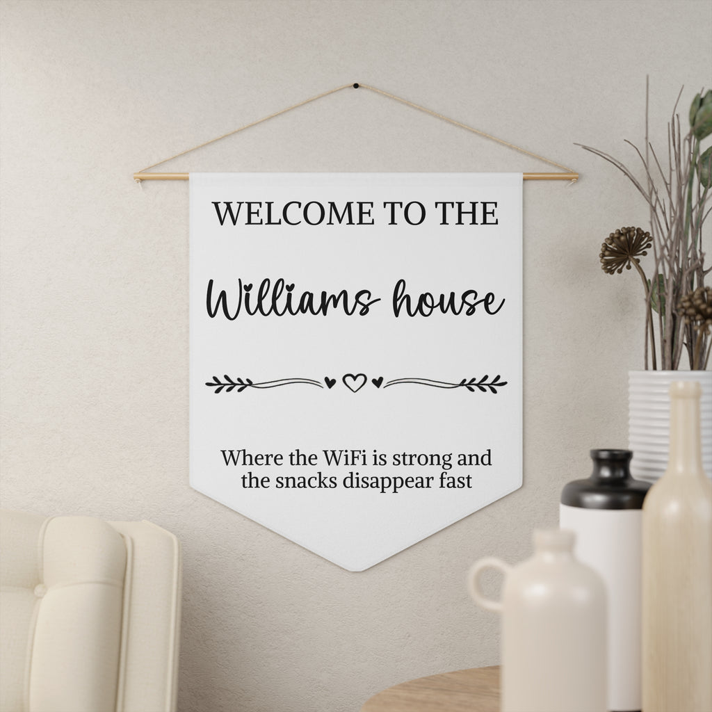 Funny welcome house pennant shown hanging on a wall as personalized entryway decor