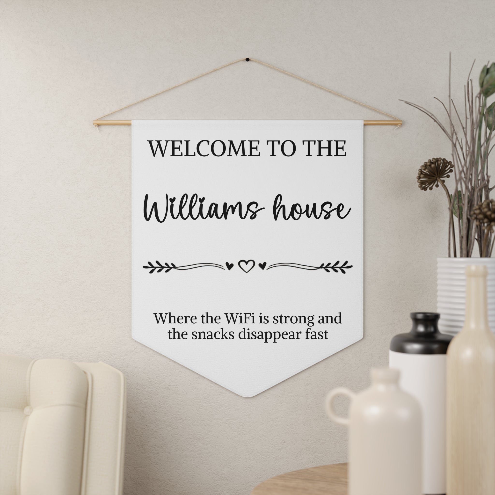 Funny welcome house pennant shown hanging on a wall as personalized entryway decor