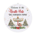 Personalized North Pole wood plaque with a family name, a North Pole signpost and decorated trees on round birch
