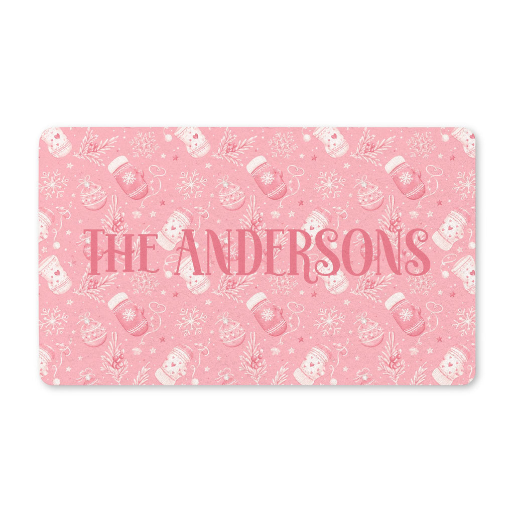 Personalized pink Christmas doormat with a family name, blush mittens, ornaments and snowflakes