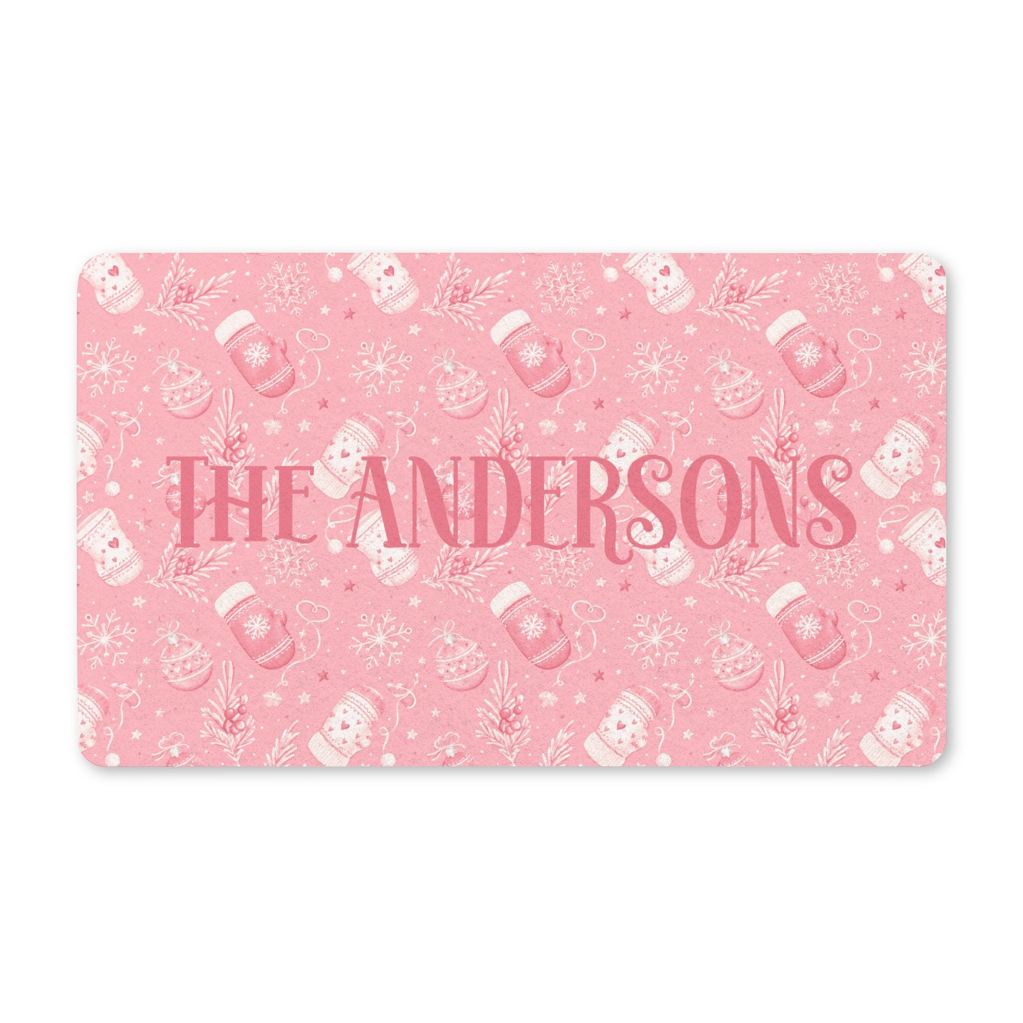 Personalized pink Christmas doormat with a family name, blush mittens, ornaments and snowflakes