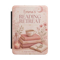 Personalized pink reading retreat Kindle case with books, a warm cup, a candle, and a custom name reading Reading Retreat