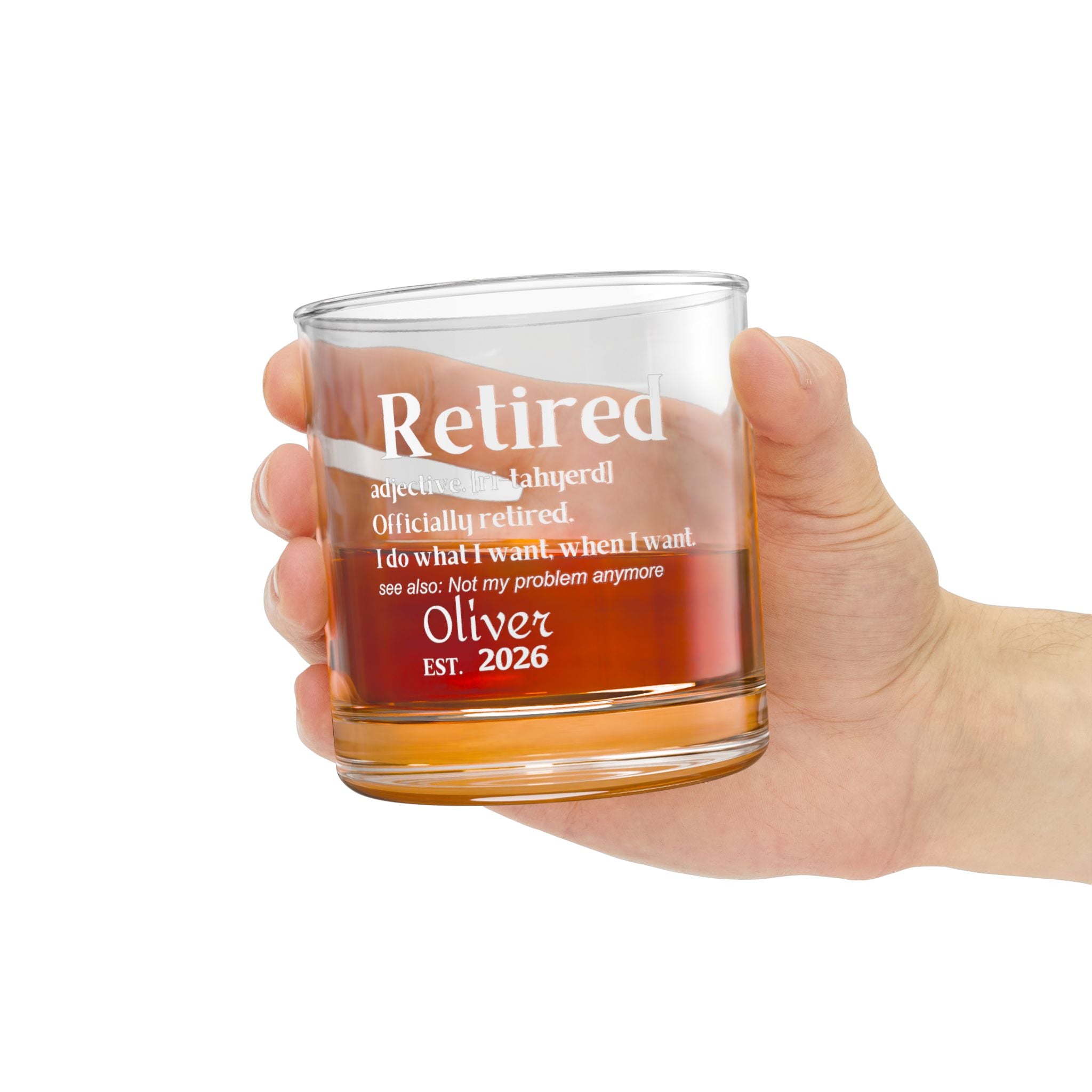 Hand holding a personalized 'Retired' definition whiskey rocks glass filled with whiskey